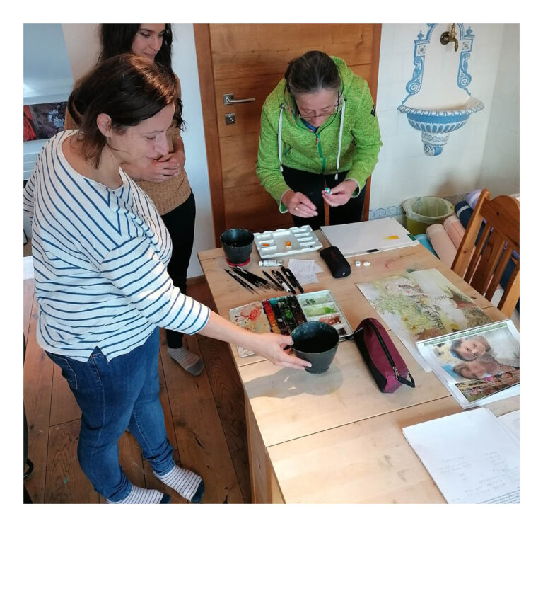 Projekt-Initiatorin Maria und die beiden Künstlerinnen wählen die Farben für das Aquarellbild aus.